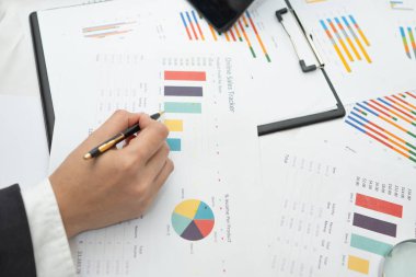 Modern ofis, finans ve iş konseptinde grafik grafik grafiği ve hesap makinesiyle çalışan ve finansal raporları analiz eden Asyalı muhasebeci.