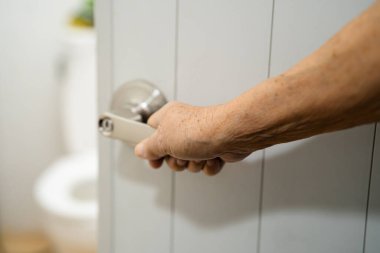 Asyalı yaşlı yaşlı kadın hasta hemşire koğuşunda tuvaleti elle açıyor. Sağlıklı, güçlü bir tıbbi konsept..