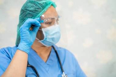 Yüz maskesi takan Asyalı bir doktor ve karantina hastanesi koğuşundaki Covid-19 Coronavirus salgınını kontrol etmek için PPE giysisi..