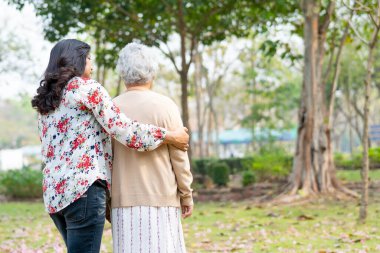Yardım ve bakım Asyalı yaşlı ya da yaşlı bir kadın mutlu bir tatilde parkta yürüyor.. 