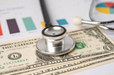Çizelge ya da grafik kağıdı, Finansal, hesap, istatistik ve iş verileri medikal sağlık kavramı üzerine steteskop ve ABD doları banknotları.