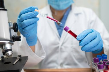 Laboratuvarda mikroskopla çalışan Asyalı biyokimyacı ya da mikrobiyolog. Coronavirus salgınını korumak için. Covid19, bakteri ve mikroplar..