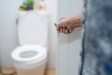 Asyalı yaşlı yaşlı kadın hasta hemşire koğuşunda tuvaleti elle açıyor. Sağlıklı, güçlü bir tıbbi konsept..