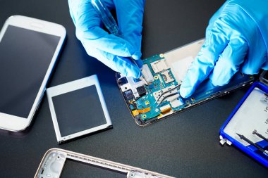 Teknisyen, cep telefonunun içinde lehim kullanarak tamir ediyor. Bütünleşik devre. veri kavramı, donanım, teknoloji.