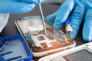 Teknisyen, cep telefonunun içinde lehim kullanarak tamir ediyor. Bütünleşik devre. veri kavramı, donanım, teknoloji.