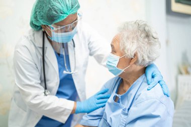 Karantina hemşire koğuşundaki Covid-19 Coronavirus salgınını kontrol etmek için yüz maskesi ve PPE kıyafeti giyen Asyalı doktor..