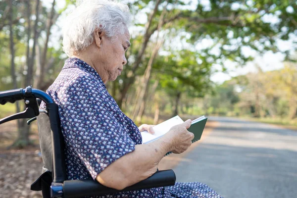 Asian senior or elderly old lady woman patient reading a book while sitting on bed in nursing hospital ward, healthy strong medical concept.