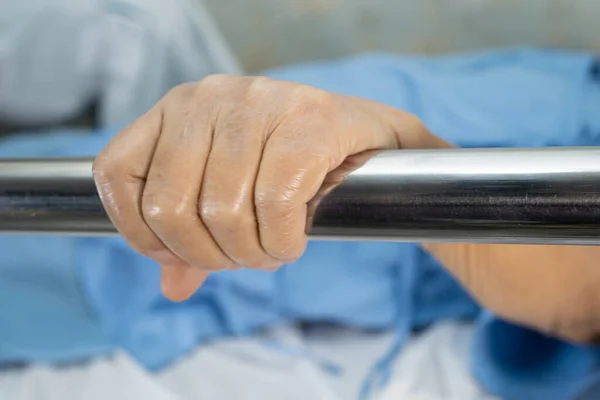 Asian senior or elderly old woman patient lie down handle the rail bed with hope on a bed in the hospital.