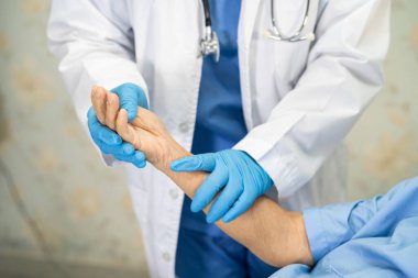 Doktor, enfeksiyon kapmasın diye hastanede yüz maskesi takan Asyalı yaşlı ya da yaşlı kadın hastaları kontrol etmek için steteskop kullanıyor..