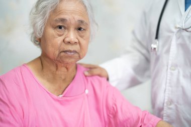 Asyalı doktor yaşlı yaşlı kadın hastaya dokunuyor. Sevgi, bakım, cesaret ve empati ile bakıcılık hastanesi koğuşunda. Sağlıklı güçlü tıbbi konsept..