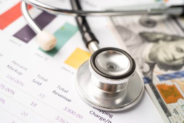 Çizelge ya da grafik kağıdı, Finansal, hesap, istatistik ve iş verileri medikal sağlık kavramı üzerine steteskop ve ABD doları banknotları.