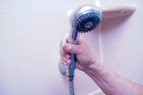 Asian senior or elderly old lady woman patient holding shower in toilet bathroom to bath in nursing hospital ward, healthy strong medical concept.