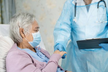 Yüz maskesi takan Asyalı bir doktor ve karantina hastanesi koğuşundaki Covid-19 Coronavirus salgınını kontrol etmek için PPE giysisi..