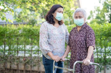 Asya 'lı yaşlı ya da yaşlı kadın Walker' la yürüyor ve güvenlik enfeksiyonu Covid-19 Coronavirus 'u korumak için maske takıyor..