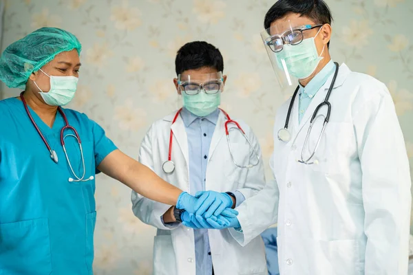 Asian doctor team stack hands together as team for motivation new normal to treat infection Covid-19 Coronavirus at hospital ward.