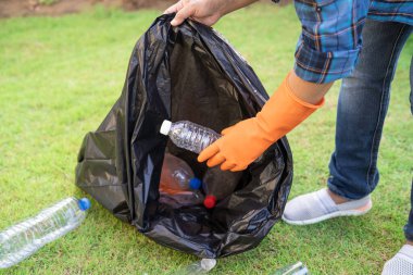 Asyalı kadın gönüllü olarak parkta çöp poşetlerine su plastik şişeleri taşıyor, çöpleri parka atıyor, çevresel ekoloji kavramını geri dönüştürüyor..