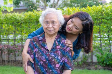 Bakıcısı olan Asyalı yaşlı kadın doğa parkında mutlu bir şekilde yürüyor..
