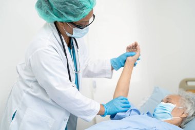 Doktor, güvenlik enfeksiyonunu korumak ve Covid-19 Coronavirus 'u öldürmek için hastanede maske takan yaşlı ve yaşlı bir kadına yardım ediyor..