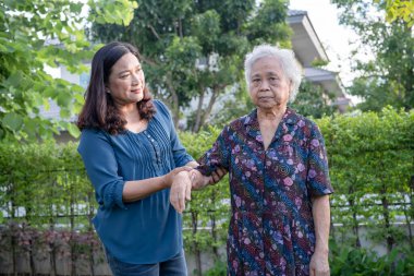 Bakıcısı olan Asyalı yaşlı kadın doğa parkında mutlu bir şekilde yürüyor..