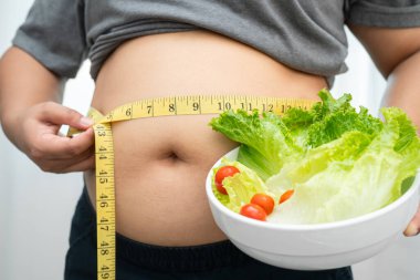 Koca göbekli, şişman, kilolu ve sağlıklı yiyecekleri olan Asyalı bir kadın..