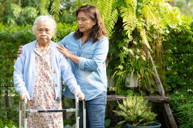 Doktor bakıcı, son sınıf Asyalı hasta Walker 'la birlikte hastanede yürüyor..