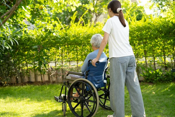 Bakıcı yardım ve bakım Asyalı yaşlı kadın hasta hemşire hastanesi koğuşunda tekerlekli sandalyede oturuyor, sağlıklı ve güçlü..