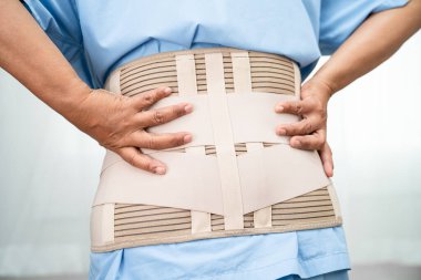 Ortopedik bel kemiği için sırt ağrısı destek kemeri takan Asyalı bir hasta..
