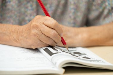 Asyalı yaşlı kadın becerilerini geliştirmek için bulmaca oynuyor..