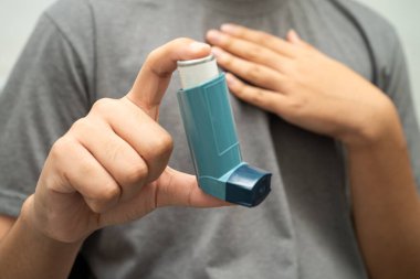 Astım ve kronik obstrüktif akciğer hastalığı COPD, Asyalı genç adam ölçülü doz solunum cihazı kullanıyor..
