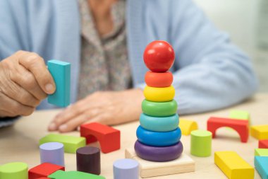 Bunama geçiren Asyalı yaşlı kadın hasta pratik motor beceri rehabilitasyonu öğreniyor.