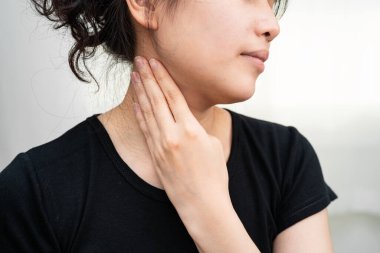 Tiroit bezi sorunu için boynuna ve boğazına dokunan Asyalı kadın..