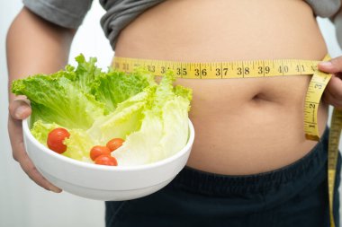 Koca göbekli, şişman, kilolu ve sağlıklı yiyecekleri olan Asyalı bir kadın..