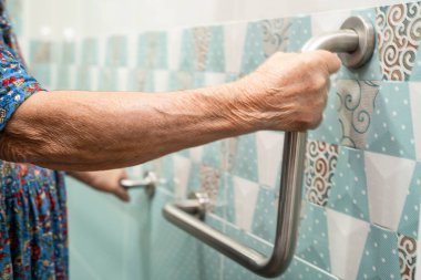 Asyalı yaşlı bir kadın tuvalette tuvalet tutacağı kullanıyor. Sağlıklı, güçlü bir tıbbi tedavi..