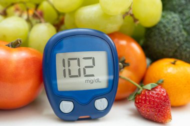 Asya 'da el ele tutuşan dijital glikoz monitörü sebze ve meyveli sağlıklı gıda ölçümü.