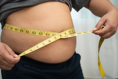 Şişman göbekli, kilolu, kilolu ve mezuralı Asyalı bir kadın..