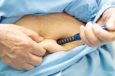 Kıdemli kadın hasta diyabet tedavisi için insülin enjekte ediyor..