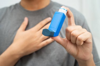 Astım ve kronik obstrüktif akciğer hastalığı COPD, Asyalı genç adam ölçülü doz solunum cihazı kullanıyor..