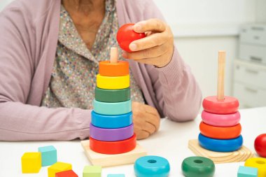 Bunama geçiren Asyalı yaşlı kadın hasta pratik motor beceri rehabilitasyonu öğreniyor.