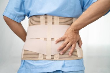 Ortopedik bel kemiği için sırt ağrısı destek kemeri takan Asyalı bir hasta..