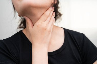 Tiroit bezi sorunu için boynuna ve boğazına dokunan Asyalı kadın..