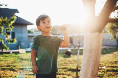 Kafkasyalı küçük bir çocuk, elinde bir elma tutuyordu ve anne babasıyla birlikte yürüyüş yaparken ağaca bakıyordu.