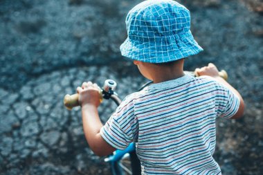 Bisiklete binen ve yaz günü şapka takan beyaz bir çocuğun üst manzara fotoğrafı.