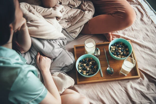 Vista superior de una pareja caucásica comiendo cereales con leche en la cama mirándose y disfrutando del tiempo juntos — Foto de Stock