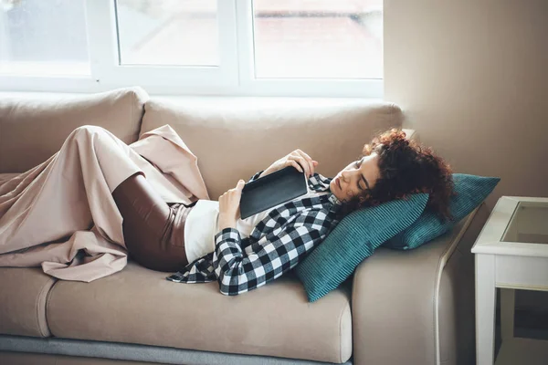 Estudiante de pelo rizado está durmiendo en la cama cubierta con una manta después de leer un libro — Foto de Stock