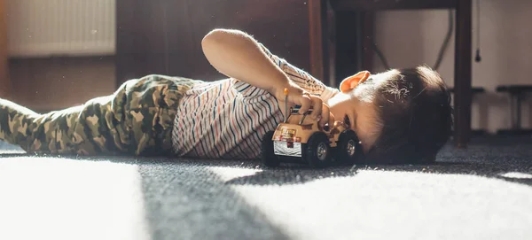 화창 한 날에 장난감 차를 가지고 바닥에서 놀고 있는 귀여운 소년 — 스톡 사진