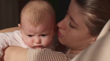 Çilli beyaz anne ve küçük kızı, annesi tarafından öpülürken ve kucaklanırken etrafına bakınıyorlar.