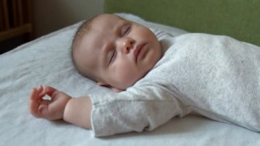 Yeni doğmuş bebek bebek uyku saatinde beyaz elbiseler giyerek yatakta rüya görüyor.