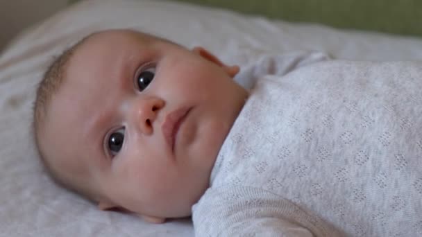 어딘가를 찾고 있는 파자마를 입고 침대에 누워 있는 신생아의 모습을 담은 근접 영상 — 비디오