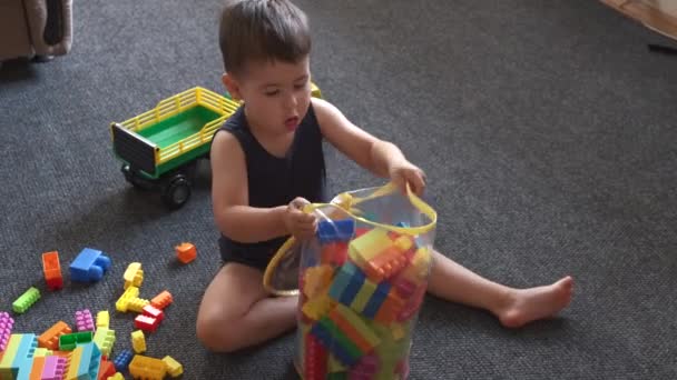 Mały biały chłopiec robi jego obowiązki czyszcząc a playgroung od konstruktor kawałki — Wideo stockowe