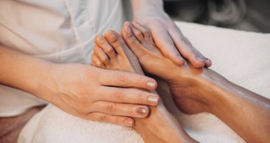 Kaplıcada yatan beyaz kadına yapılan ayak masajı prosedürü.